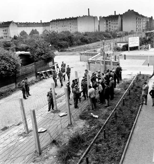 West Berliners on the right talk with East Berlin policemen through the barbed wire fence in 1961