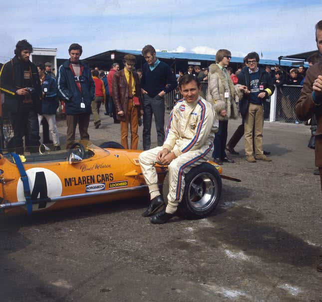 New Zealand motor-racing driver Bruce McLaren sits on the wheel of his McLaren-Ford M14A before the start of the 1970 Race of Champions at Brands Hatch in Kent.