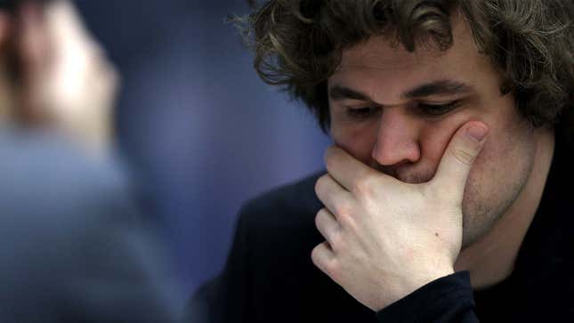 A photo shows Magnus Carlsen with his hand on his face. 