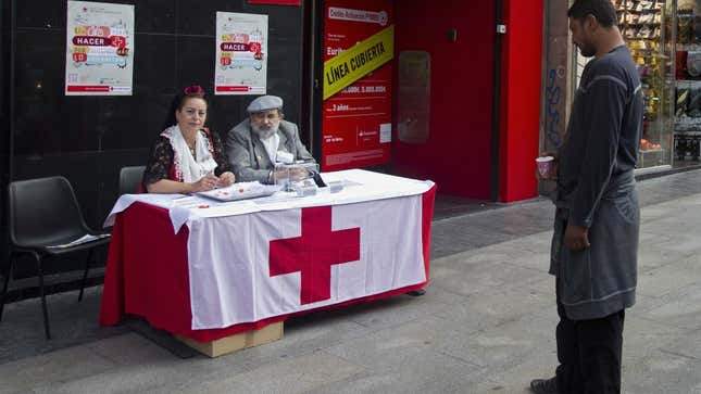 A man begging in front of a Red Cross donations table in Madrid this month