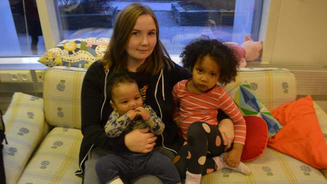 A mom holder her son and daughter on the couch in a family cafe