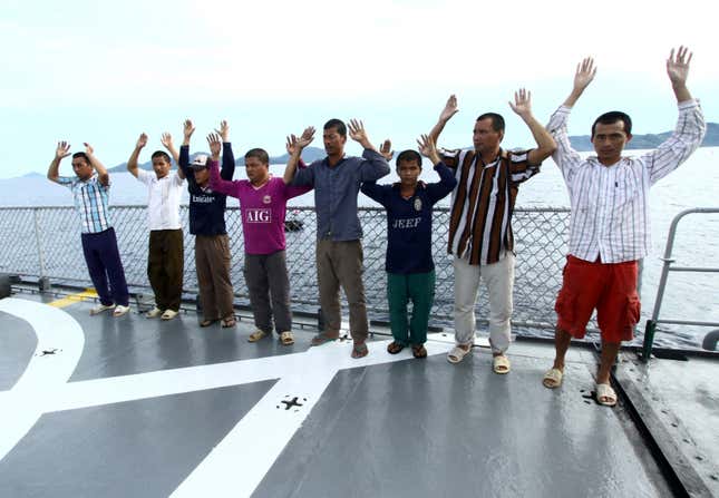 Vietnamese fisherman raise their hand as they are detained onboard an Indonesian warship.