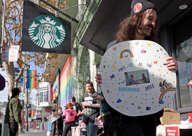 Striking Starbucks worker Kyle Trainer holds a sign outside of a Starbucks coffee shop during a national strike on November 17, 2022 in San Francisco, California. Thousands of members of the Starbucks Workers Union are striking at over one hundred Starbucks stores across the country as workers try to negotiate a contract with Starbucks. The one day strike is taking place on Red Cup Day, when Starbucks gives customers limited-edition reusable red holiday cups, one of the company's most profitable days of the year.