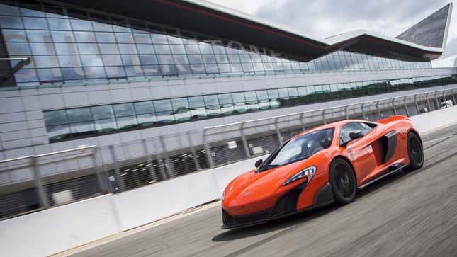 A photo of an orange Mclaren supercar driving at the Silverstone circuit. 