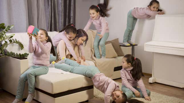 Tired mother on couch, with girls jumping up and down