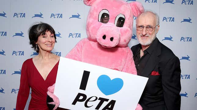 James Cromwell and Anna Stuart standing on either side of a costumed pig mascot holding a sign reading "I Love PETA"