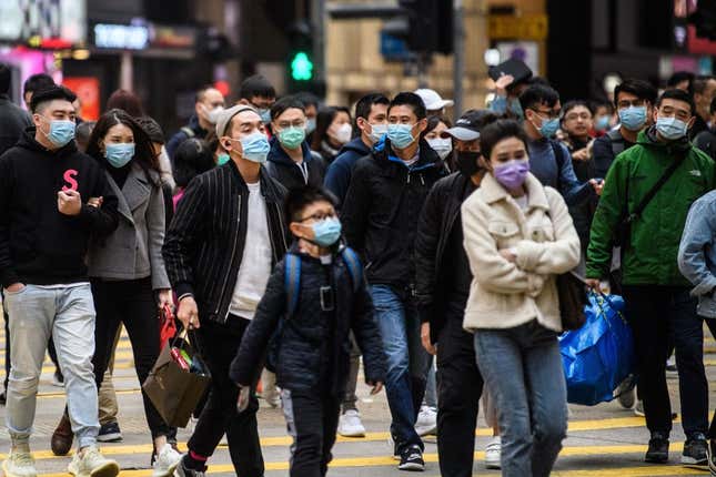 Pedestrians wearing face masks cross a road during a Lunar New Year of the Rat public holiday in Hong Kong on January 27, 2020, as a preventative measure following a coronavirus outbreak which began in the Chinese city of Wuhan.