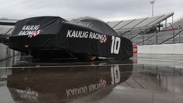A photo of a NASCAR racer under a cover in the rain. 