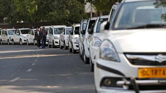 Drivers of Uber and Ola walk next to their parked vehicle's during a protest in New Delhi