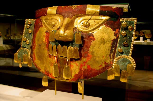 A Sicán funerary mask, painted red.