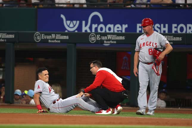 Jun 15, 2023; Arlington, Texas, USA; Los Angeles Angels third baseman Gio Urshela (10) is looked at by the trainer after injuring his knee in the first inning against the Texas Rangers at Globe Life Field.