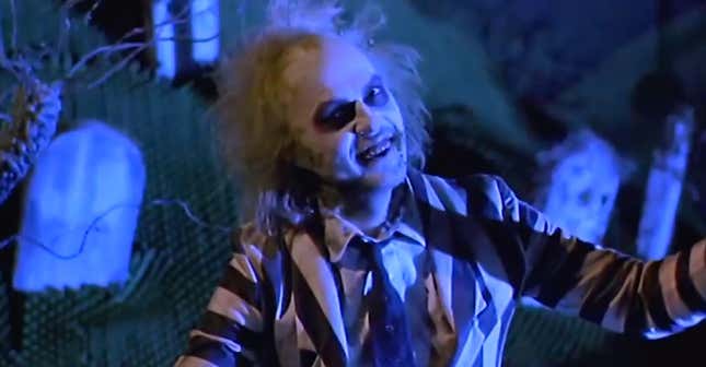 Michael Keaton as Beetlejuice, popping out of his cemetery in his iconic black-and-white striped suit.