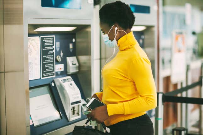 Black woman with mask at ATM 