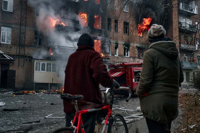 Two people look at burning building