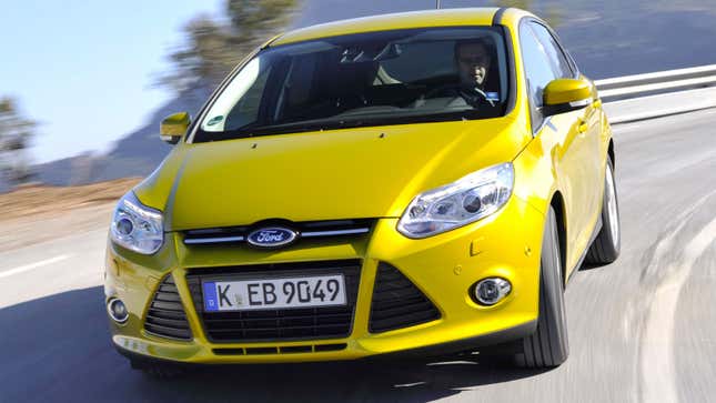 A photo of the front end on a yellow Ford Focus hatchback. 
