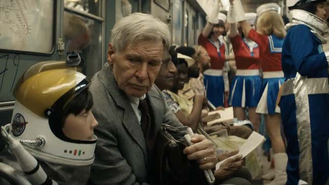 The elderly Indiana Jones sits on a subway war, staring at a kid in an astronaut suit.