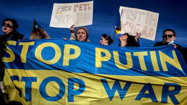 Protestors weep as they hold multiple posters and a banner reading "Stop Putin Stop War" while organizing in Rome,