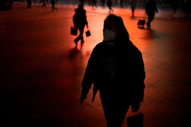A woman wearing a mask walks outside the Shanghai Railway Station in China.
