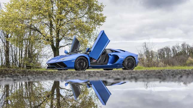 The open doors on a blue Lamborghini Aventador LP 780-4 Ultimae reflected in a pond