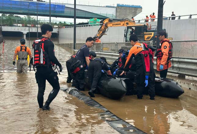 South Korea National Fire Agency, rescuers work to search for survivors along a road submerged by floodwaters leading to an underground tunnel in Cheongju, South Korea, on July 16, 2023.