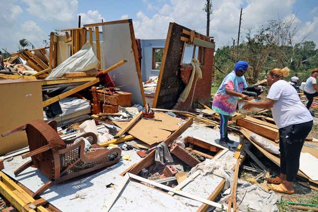 Brenda Gavin (L) and Jaliyah Shelby (R) help remove belongings from the tornado-damaged home of Elnora Ross on June 19, 2023 in Louin, Mississippi.