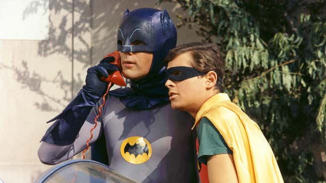 Batman and Robin take a call on a red telephone.