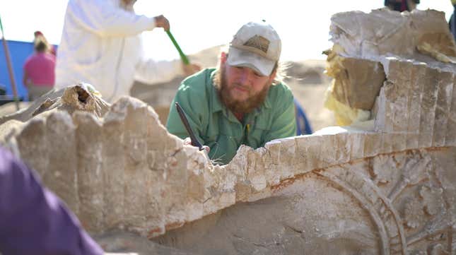 Archaeologist Ryan Wendel brushes sand off the sphinx.