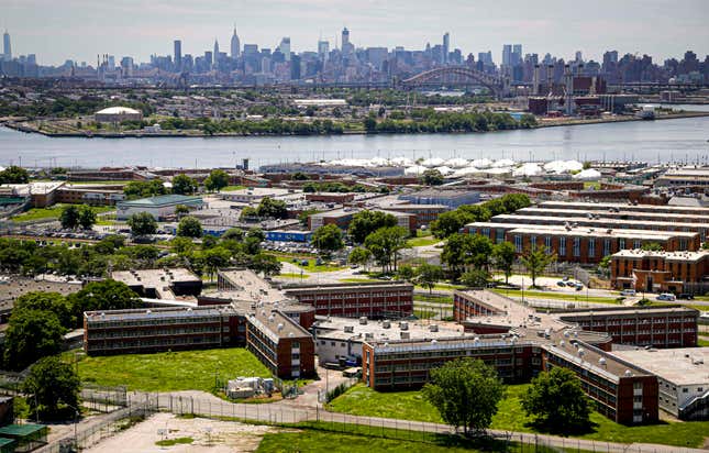 This Tuesday Dec. 2, 2014, file photo shows the Rikers Island jail complex in the foreground within the East River and the New York skyline in the background. Gov. Kathy Hochul on Tuesday, Sept. 28, 2021, declared a disaster emergency and signed an executive order expanding the use of virtual court appearances at Rikers Island jail, saying it would expedite hearings for inmates and lessen some of the burden on corrections officers at a facility in crisis. (AP Photo/Seth Wenig, File)