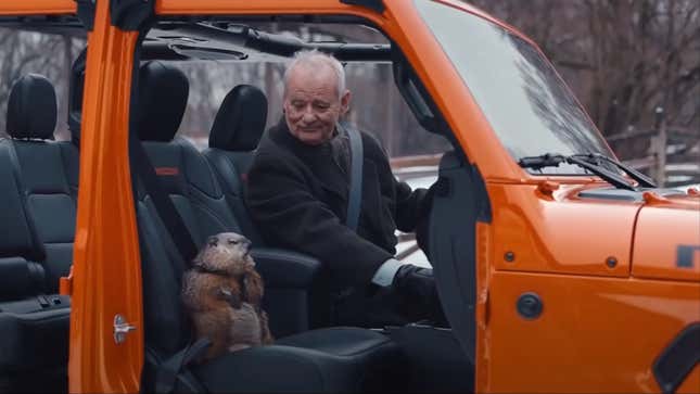 Bill Murray looks down at the groundhog in the passenger seat of his doorless orange Jeep Gladiator.