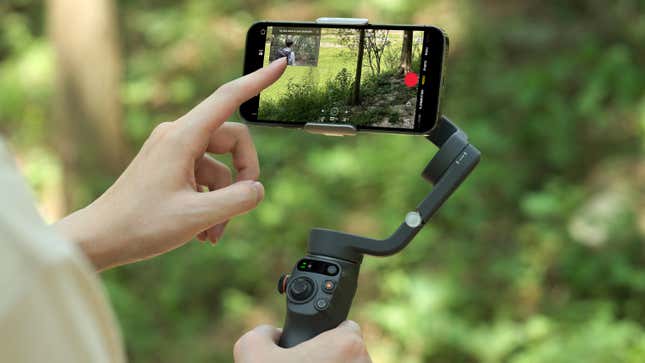 A user interacting with a smartphone attached to the DJI Osmo Mobile 6 stabilizer.