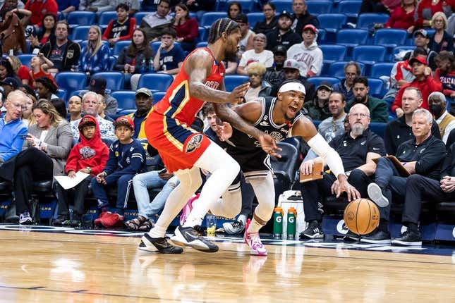 Mar 21, 2023; New Orleans, Louisiana, USA;  San Antonio Spurs guard Devonte&#39; Graham (4) dribbles against New Orleans Pelicans forward Naji Marshall (8) during the first half at Smoothie King Center.
