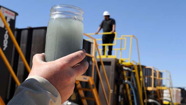 A jar holding waste water from hydraulic fracturing is held up to the light at a recycling site in Midland, Texas.