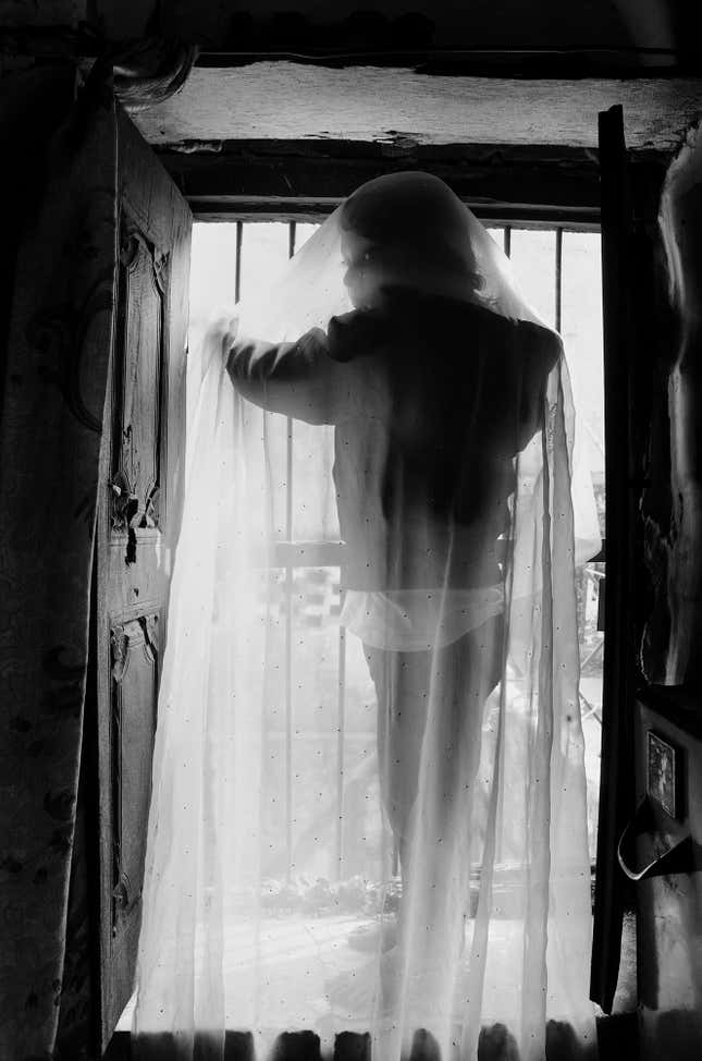 Umrah peeps through a broken window in her house in Deorhi Agha Meer, Old Lucknow.