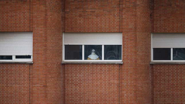 A health worker wearing a protective suit stands at a window in the isolation ward of the Carlos III hospital in Madrid.