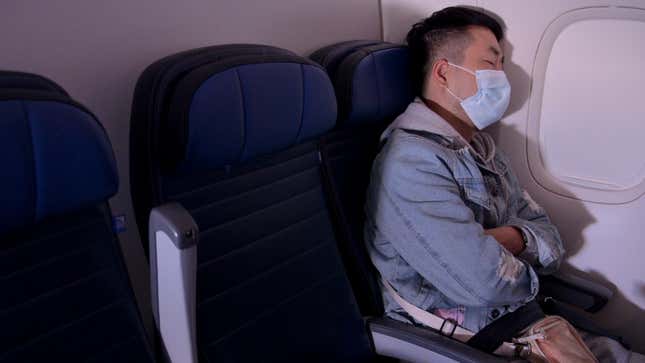 IN FLIGHT - OCTOBER 27: A masked passenger is seen sleeping on a flight from San Francisco, California to Newark, New Jersey.