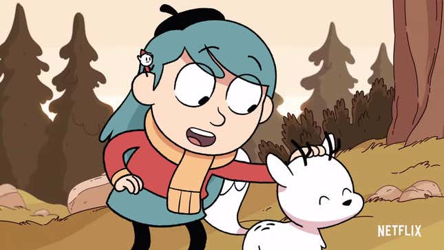 In a screenshot from the animated series Hilda, a little girl with blue hair (Hilda) pets a small fox magical fox with antlers in a forest
