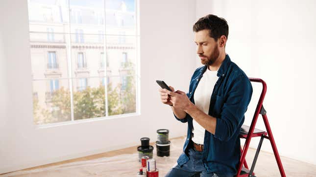 Young man with phone in house that he's about to paint