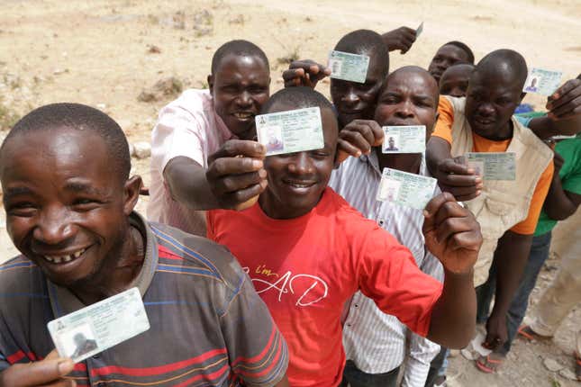 People displace by Islamist militants display their voters card