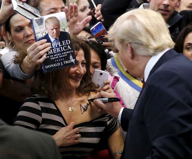 Republican presidential candidate Donald Trump (R) autographs the chest of a woman at his campaign rally in Manassas, Virginia on Dec. 2, 2015.