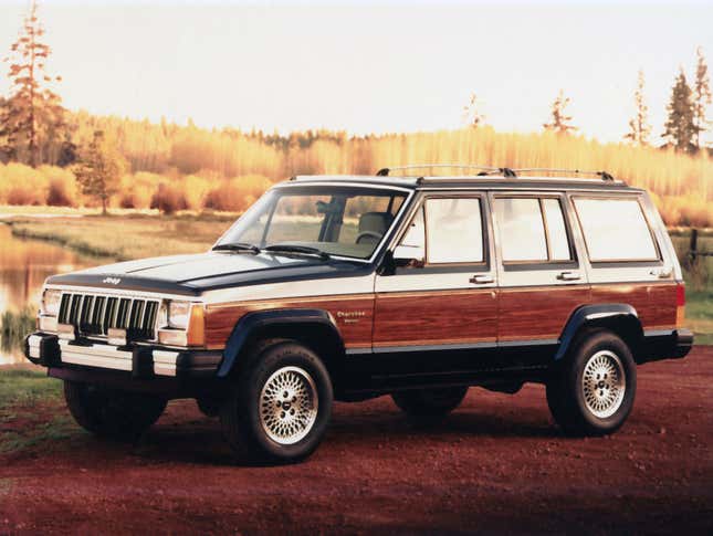 A 1991 Jeep Cherokee is parked on dirt. It has wood-look appliques on its sides.