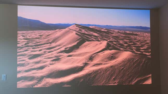 A scene featuring sand covered hills in a desert projected onto a wall by the JMGO N1 Ultra projector.