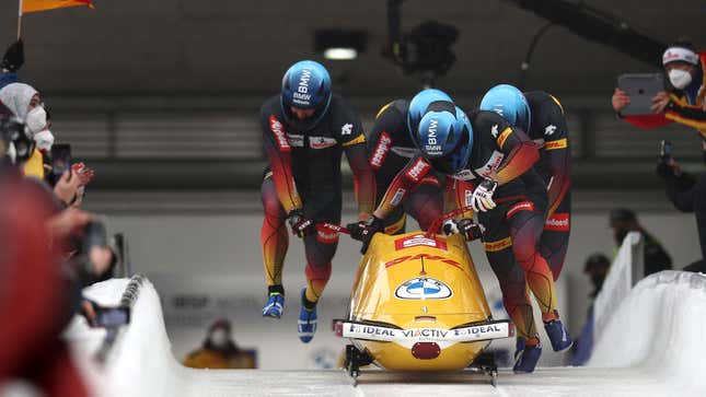 A photo of German athletes pushing a BMW bobsled. 