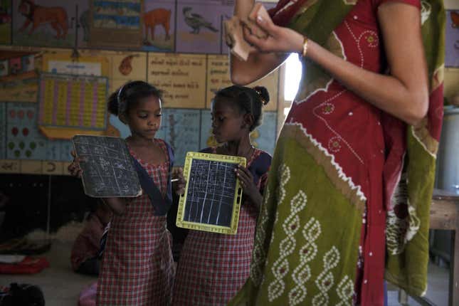 Two Sidi girls go to show their teacher their schoolwork in her villages school.