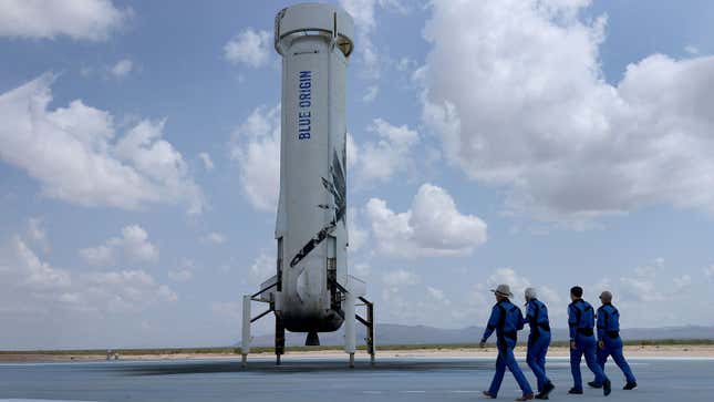 Four people walk towards the Blue Origin space craft