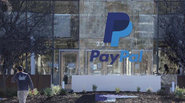 A man walks by a large sign with the PayPal logo on it in front of the PayPal headquarters in San Jose, California.