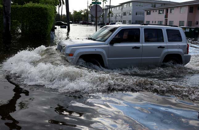 A vehicle drives through a flooded street after record rains fell in the area on April 13, 2023 in Hollywood, Florida. The heavy rain yesterday caused flooding as the region recorded rainfall totals of more than a foot.