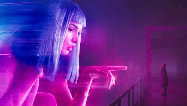 A screenshot of Blade Runner 2049 featuring a giant blue haired hologram of a woman pointing at Ryan Gosling's character on a dark balcony