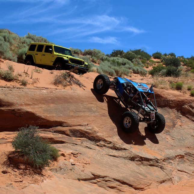 A photo of a Jeep Wrangler winching a dune buggy up a cliff. 
