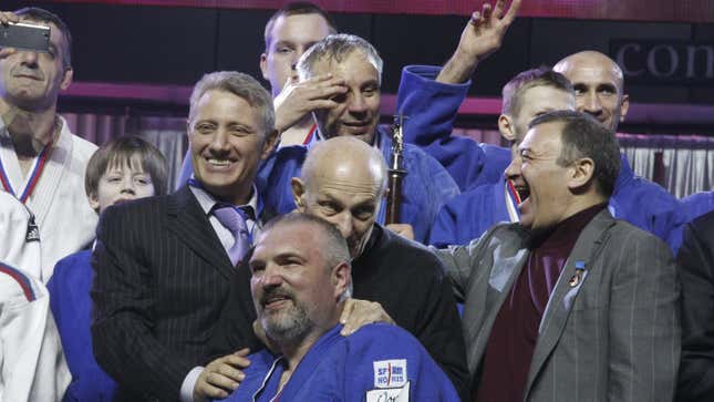 Boris Rotenberg (left, front, wearing a black jacket) and Arkady Rotenberg (right, front, wearing a grey jacket) react during an awarding ceremony of a judo competition in St. Petersburg, 2012.