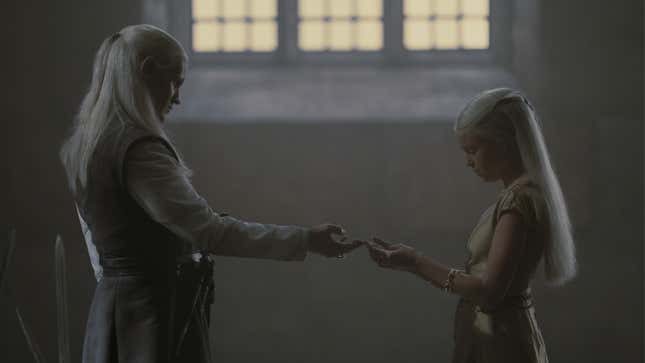 Daemon Targaryen hands his niece Rhaenyra a gift in the throne room.